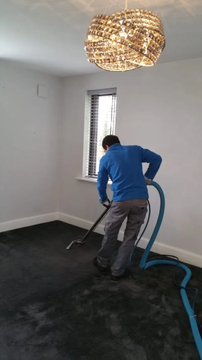 A technician working a carpet cleaning wand across a carpet, the stage at which protector would be applied afterward