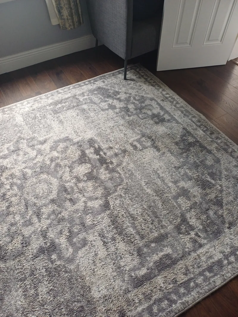 A rug laid over a hardwood floor, the kind of setting common for natural-fibre rugs
