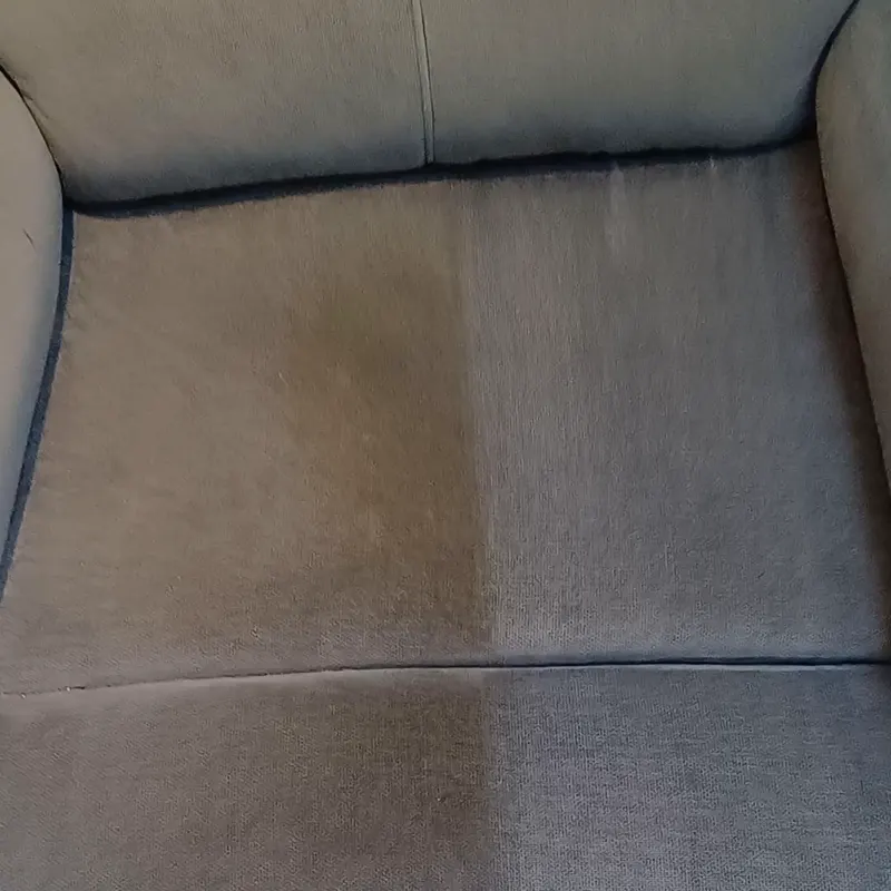 A grey fabric armchair back with one half cleaned and the other still soiled