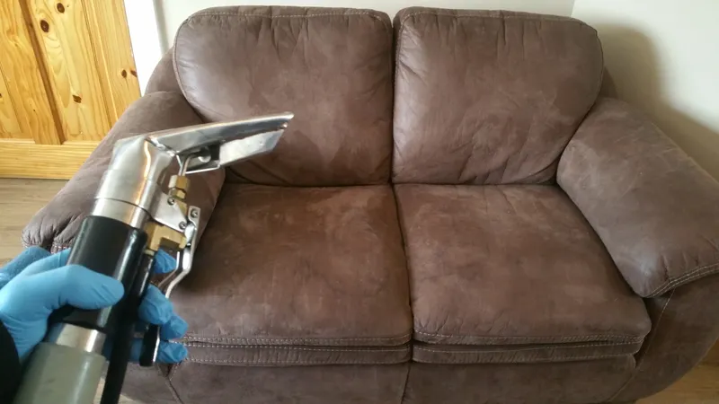 Technician cleaning a fabric sofa with an upholstery tool